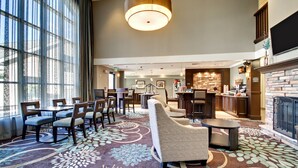 Een hotel lobby met een ruim zithoek, een open haard, en een keuken op de achtergrond.