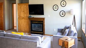 Ein Wohnzimmer mit Kamin, Flachbildfernseher und Sofa.