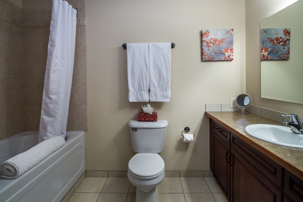 A bathroom with a bathtub, toilet, sink, and two wall-mounted mirrors.
