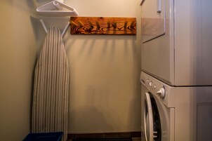A laundry room with a wall-mounted drying rack, a wooden decorative piece, and a front-loading washing machine.