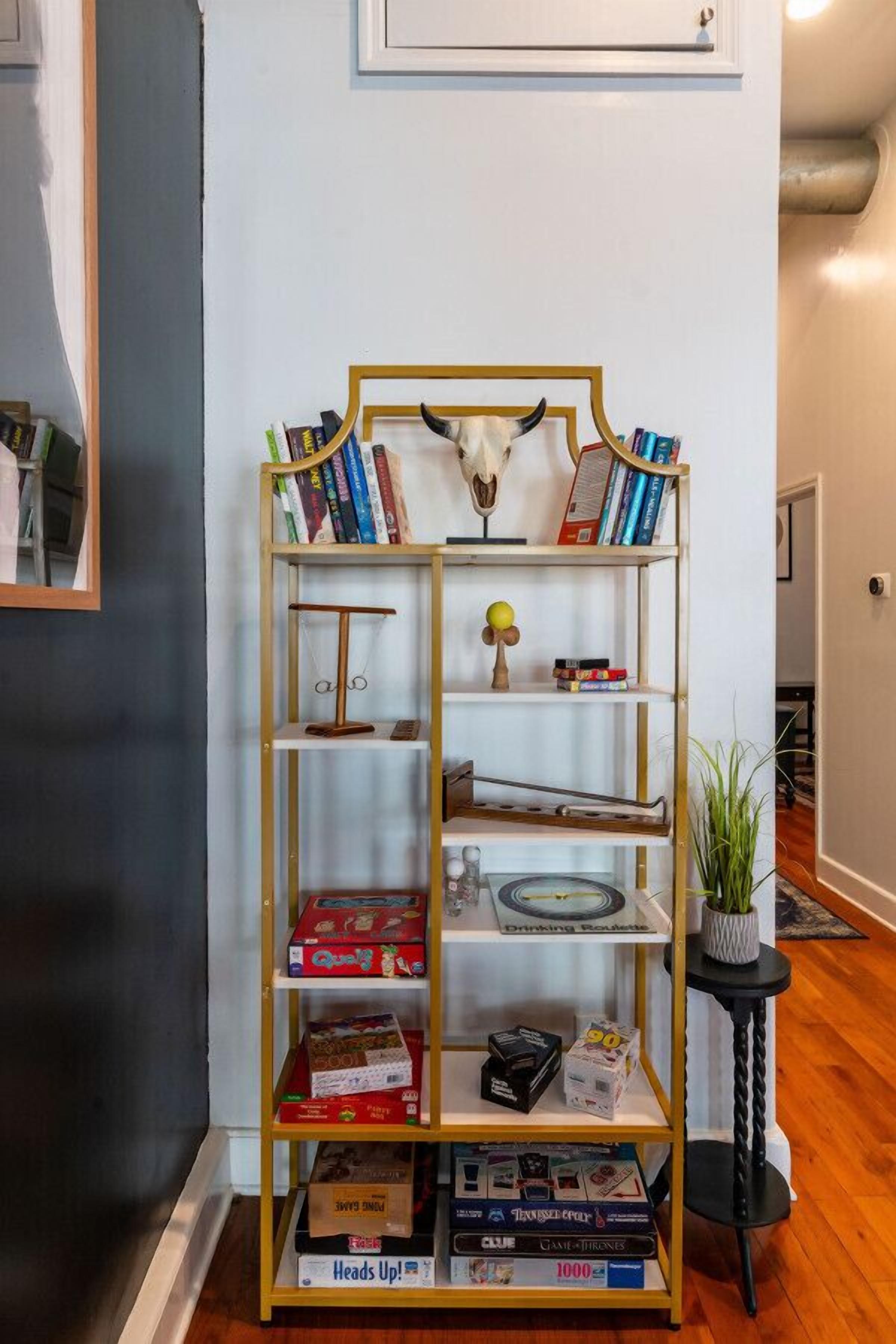 A bookshelf with various items including books, a scale, and board games.