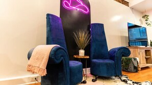 A modern living room with two blue velvet armchairs, a neon heart-shaped light, and a small side table with a plant. - Jump right into the heart of Downtown Knoxville (Knoxville)