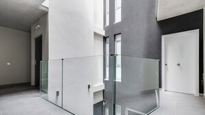 Un intérieur moderne avec une cloison en verre, une porte et un sol carrelé.