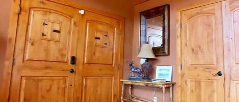A hallway with wooden doors, a tiled floor, and a small table with a lamp and decorative items.