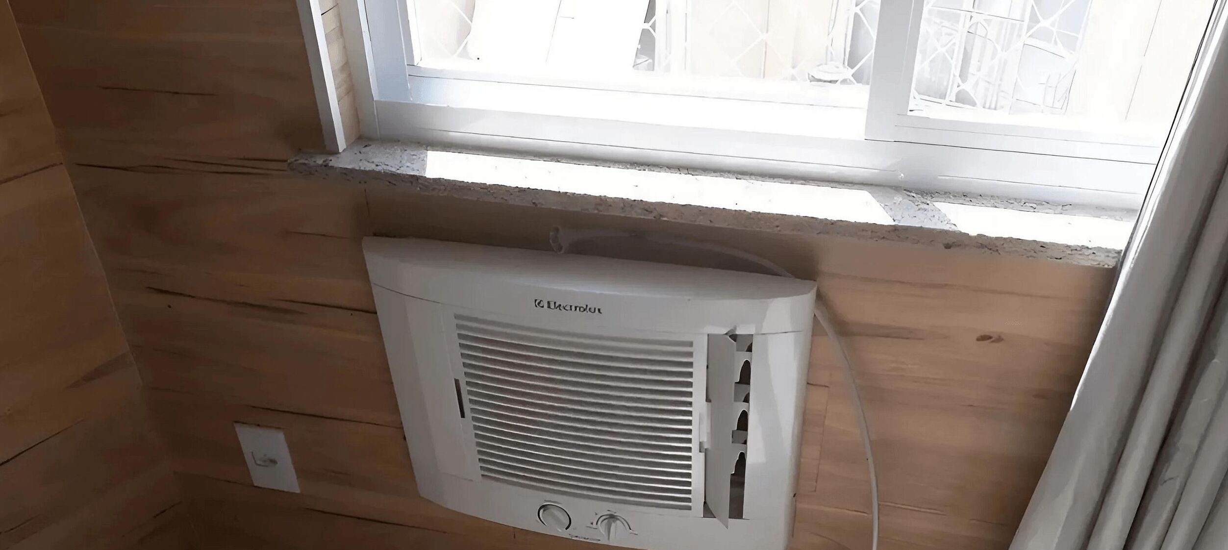 Une pièce aux murs en bois, avec une fenêtre et un radiateur blanc fixé au mur.