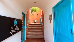 A hallway with a turquoise door, a staircase, and a sign reading "Zana Rosa". - Zona Rosa 75, San Antonio (Santa Fe)