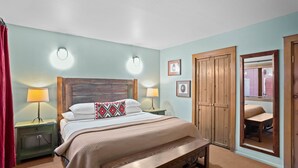 A bedroom with a wooden bed, two bedside lamps, a nightstand, a bench, a wardrobe, and a mirror. - Zona Rosa 75, San Antonio (Santa Fe)