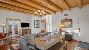 A living room with a wooden ceiling, a TV, a sofa, a dining table, and a fireplace. - Zona Rosa 76, Santa Rita (Santa Fe)