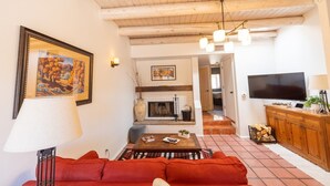 A living room with a fireplace, red sofa, wooden ceiling, and a TV. - Zona Rosa 73, Santa Barbara (Santa Fe)