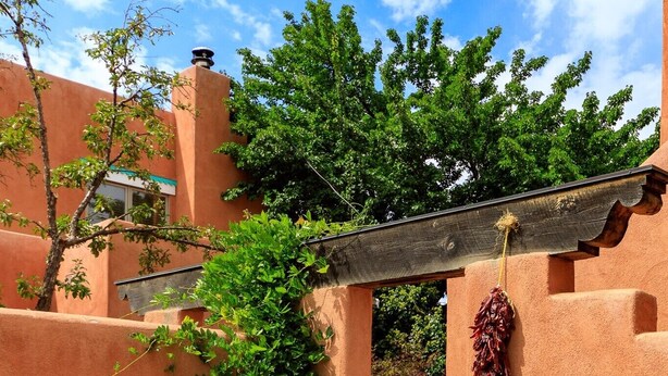 A courtyard with a wooden pergola, a hanging dried chili pepper, and potted plants. - Zona Rosa 73, Santa Barbara (Santa Fe)