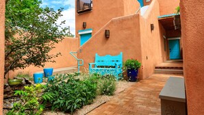 A courtyard with a blue bench, potted plants, and a stone wall. - Zona Rosa 73, Santa Barbara (Santa Fe)