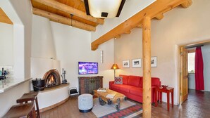 Un salon chaleureux avec une cheminée, un canapé rouge, une table basse en bois et un téléviseur.