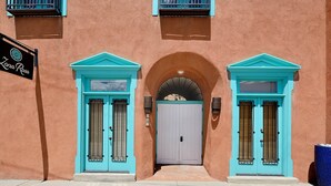 Un bâtiment aux portes et fenêtres turquoise, une enseigne indiquant «La Rosa», et une entrée en arc de cercle.