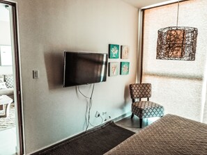 Relax in a stylish room with a flat-screen TV, patterned armchair, and pendant light.