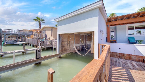 A wooden deck with a pool, a small building with a large window, and a covered area with a blue chair. - Lugo Fishing Paradise in Historic Port Isabel (Port Isabel)