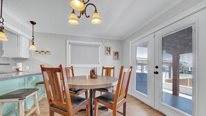 A dining area with a round table, wooden chairs, and pendant lighting. - Lugo Fishing Paradise in Historic Port Isabel (Port Isabel)