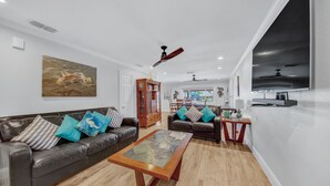 A modern living room with a leather sofa, a wooden coffee table, and a large painting on the wall. - Lugo Fishing Paradise in Historic Port Isabel (Port Isabel)