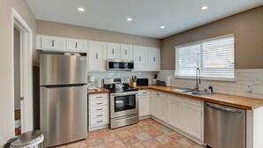 A modern kitchen with white cabinets, stainless steel appliances, and a wooden countertop. - Quiet, Cozy Townhouse w/ all new appliances and furniture. (Shreveport)