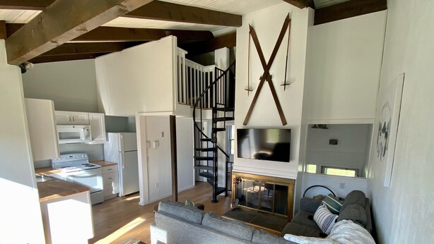 Un espacio habitable moderno y abierto, con cocina, comedor y una escalera que sube a un nivel superior.