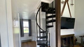 Un interior moderno con una escalera espiral, piso de madera y una chimenea.