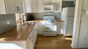 Una cocina con gabinetes blancos, un microondas, una estufa y un refrigerador.