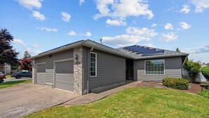 Une maison à deux étages avec un garage, des panneaux solaires sur le toit et une pelouse bien entretenue.