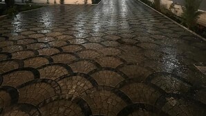 Un espacio exterior nocturno con un sendero pavimentado, iluminado por luces empotradas en la pared.