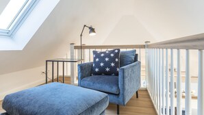 A loft bedroom with a skylight, a desk, a chair, and a sofa. - Appartement Friesenloft (Sylt-Ost)