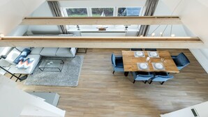 A modern loft-style apartment with a dining area, seating, and a view of the outdoors. - Appartement Friesenloft (Sylt-Ost)