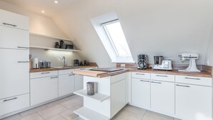 A modern kitchen with white cabinets, a wooden countertop, and a skylight. - Appartement Friesenloft (Sylt-Ost)