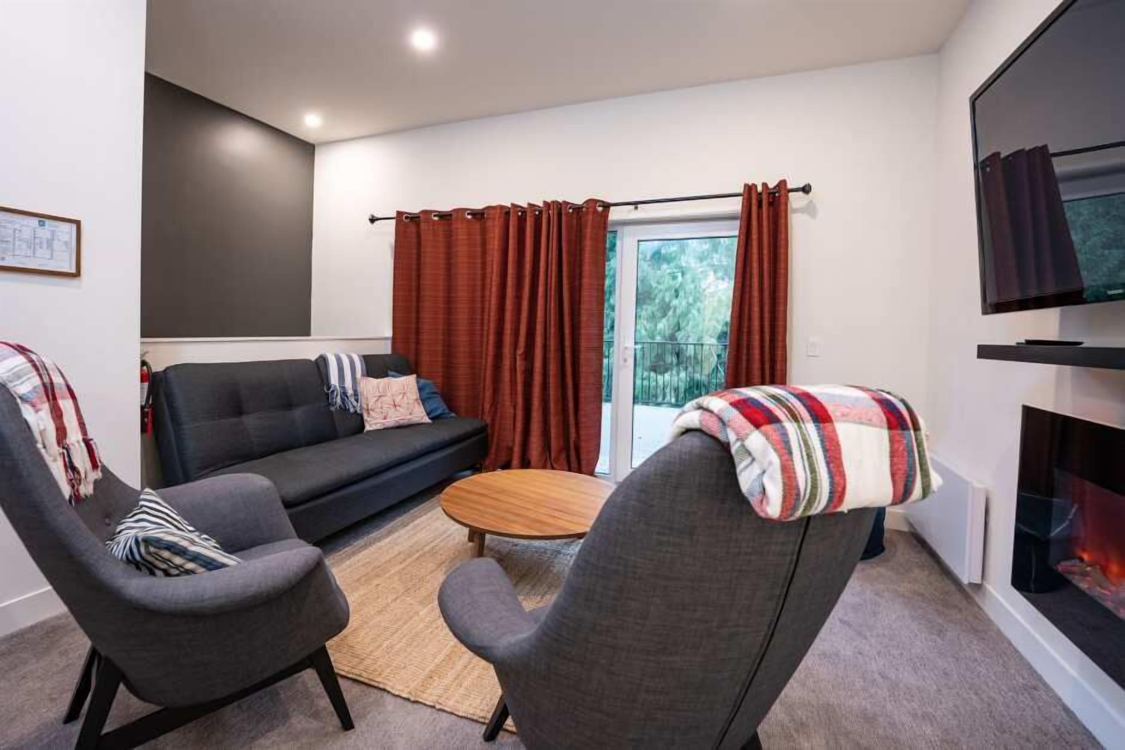 A modern living room with a sofa, two armchairs, a coffee table, and a fireplace.
