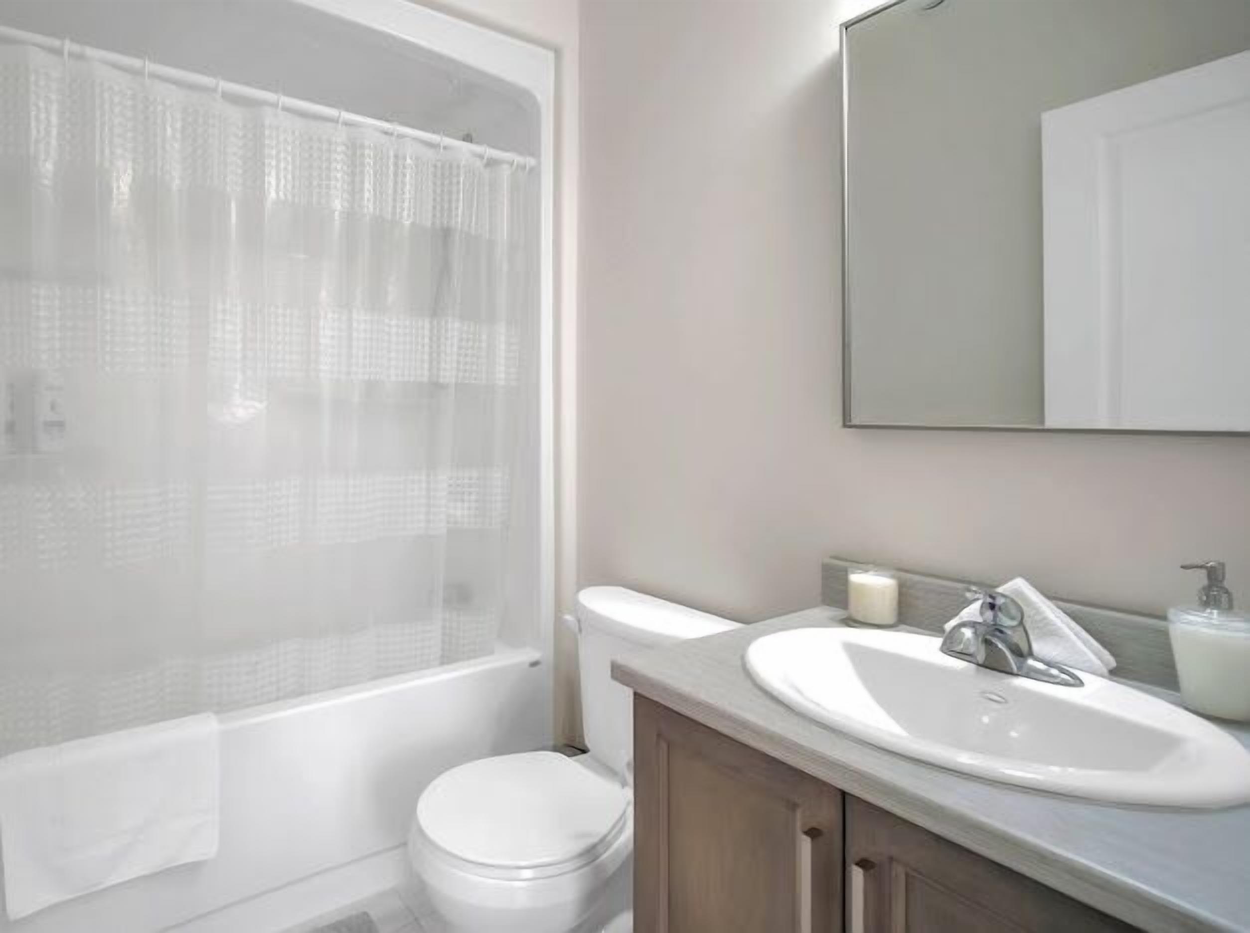 A bathroom with a bathtub, toilet, sink, and mirror.