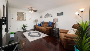 A living room with a brown leather sofa, a coffee table, a TV, and a ceiling fan. - Enjoy a Peaceful Get-Away - Self check -in (San Antonio)