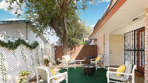 A backyard with a white fence, a tree, and outdoor furniture including chairs and a table. - Enjoy a Peaceful Get-Away - Self check -in (San Antonio)