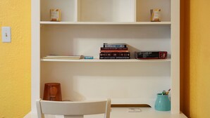 A white desk with a chair, a bookshelf with books and a game set, and a teal mug with pens. - Enjoy a Peaceful Get-Away - Self check -in (San Antonio)