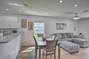 A modern kitchen with white cabinets, a granite countertop, and a dining area with a table and chairs.