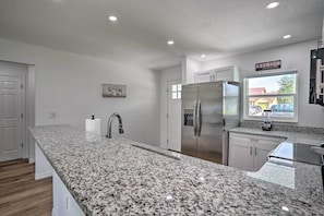 A modern kitchen with granite countertops, stainless steel appliances, and a view of the outside through a window.