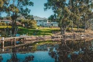 A lakeside property with a dock, a grassy lawn, and a house in the background.