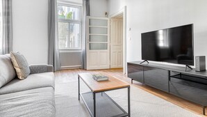En moderne stue med sofa, sofabord, fjernsyn og skab.