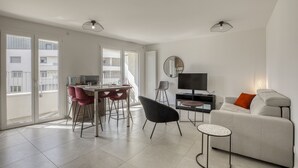 En moderne stue med spiseplads, sofa, fjernsyn og en balkon med store vinduer.