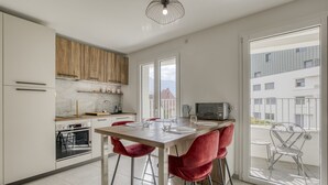 Et moderne køkken med træbordplade, indbygget ovn og spiseplads med røde stole.