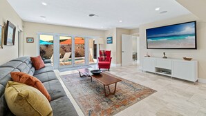 Ein geräumiges Wohnzimmer mit einer großen Eckcouch, einem Couchtisch und einem flachbildfernseher, der an der Wand befestigt ist.