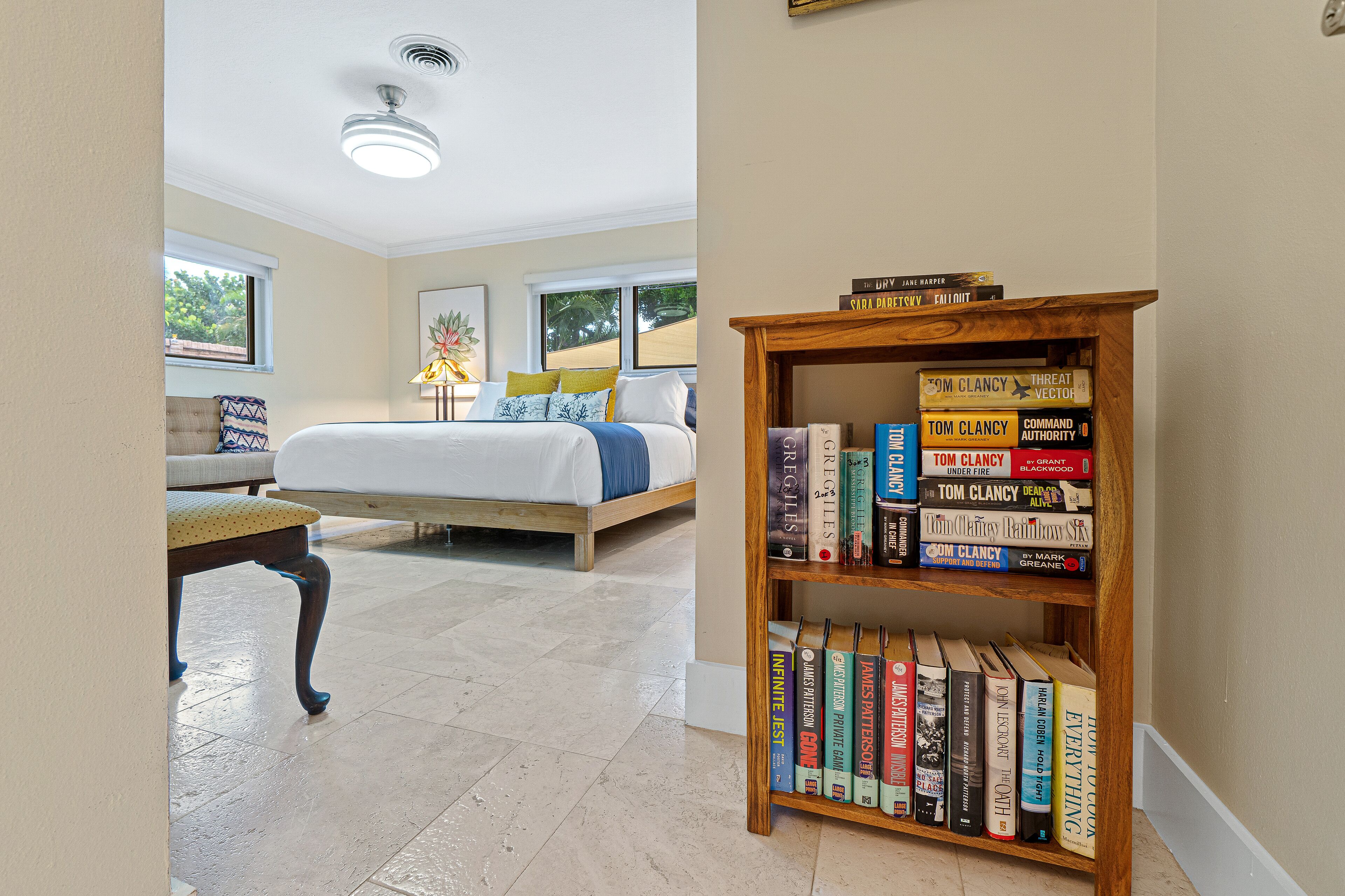 A bedroom with a bed, a wooden bookshelf, and a window.
