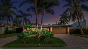 Ein Wohnhaus mit Garage, umgeben von Palmen und einem gepflegten Rasen.