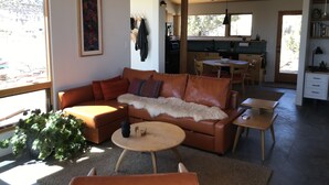 A cozy living room with a brown leather sofa, a small round table, and a potted plant.
