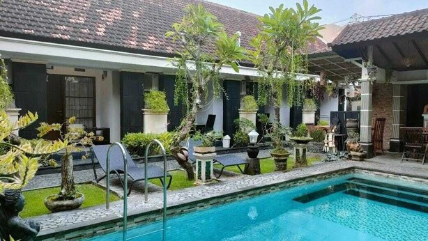 A swimming pool with lounge chairs and potted plants.