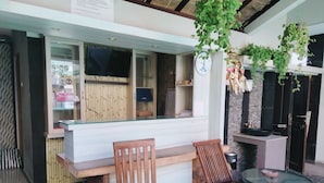 A restaurant with a counter, wooden chairs, and a glass table.