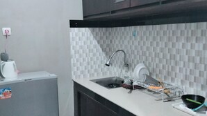 A compact kitchen with a refrigerator, a sink, and a dish rack.