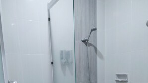 A small, modern bathroom with a toilet, a glass shower enclosure, and a white tiled floor.