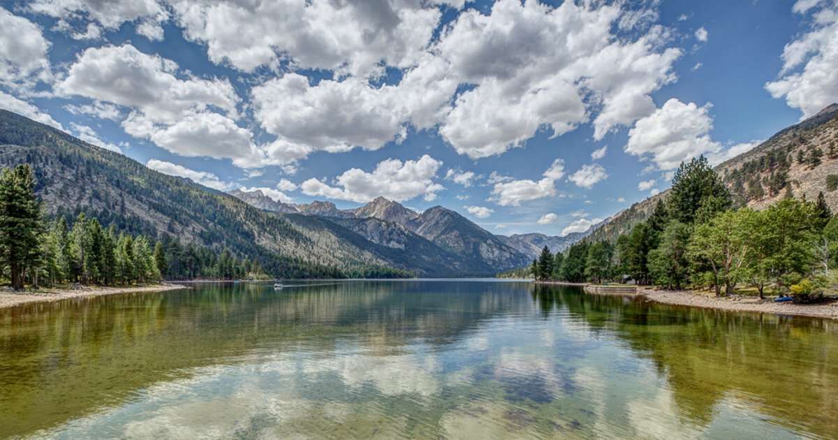 A calm lake surrounded by mountains and trees.